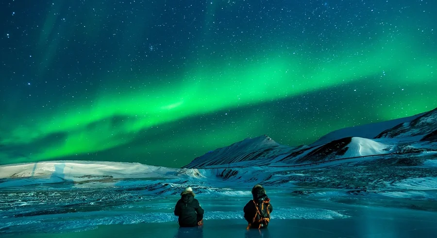 visit alaska aurora night sky with couple sitting on ice