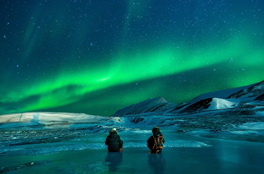 visit alaska aurora night sky with couple sitting on ice